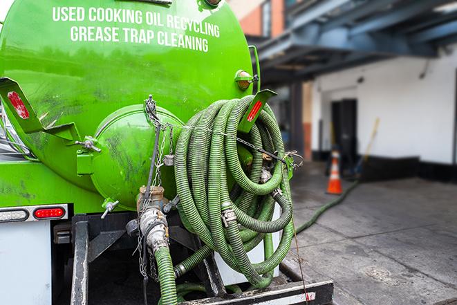 worker pumping grease trap at commercial kitchen in Cherryville